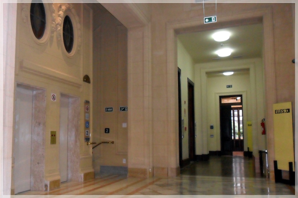 A foto mostra o hall dos elevadores e corredor que dá acesso à exposição.